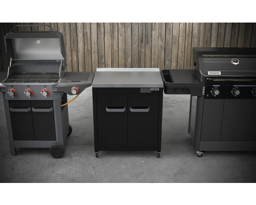 Tři grilovací zařízení s venkovním úložným prostorem před dřevěnou stěnou