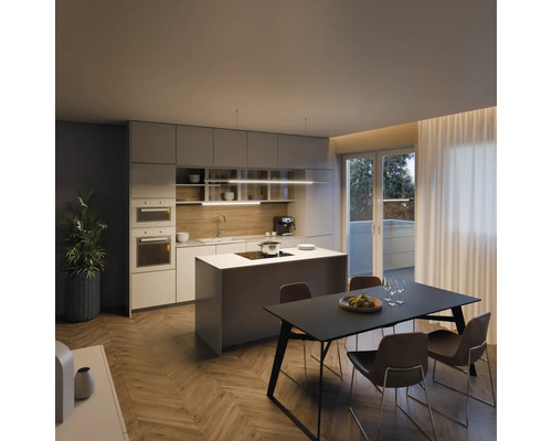 Moderní kuchyně s kuchyňským ostrovem, jídelním stolem a židlemi ve světlé místnosti.