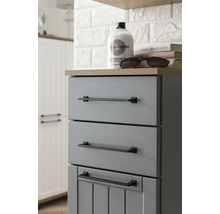 Šedá koupelnová skříňka se třemi zásuvkami a černými úchyty.