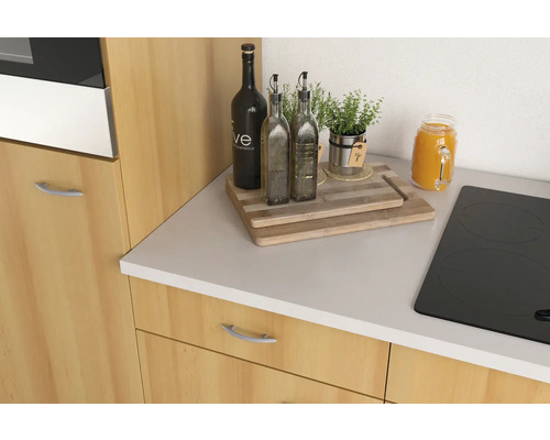 Kuchyňské zátiší s lahvemi oleje, bylinkami a prkénkem na kuchyňské desce