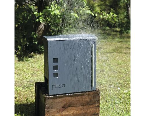 Déšť padá na šedou poštovní schránku na dřevěné bedně.