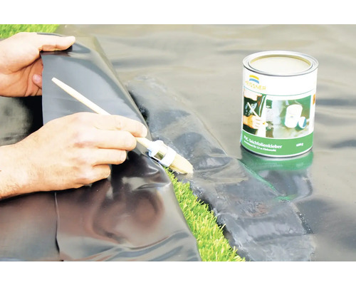 Aplikace lepidla na jezírkové fólie štětcem na černou jezírkovou fólii.