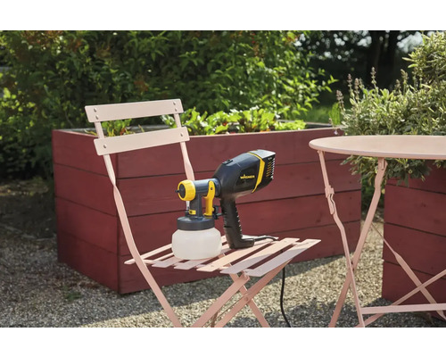 Stříkací systém Wagner na zahradní židli vedle stolu a vyvýšeného záhonu