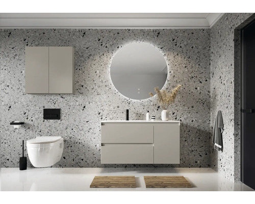 Moderní koupelna s umyvadlem, zrcadlovou skříňkou, toaletou a kulatým zrcadlem s osvětlením před vzorovanou stěnou