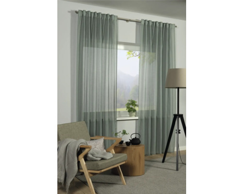 Obývací pokoj s oknem a závěsy, křeslo, konferenční stolek a stojací lampa