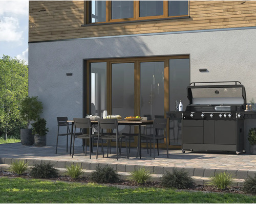 Terasa s jídelním stolem, židlemi a plynovým grilem před rodinným domem.