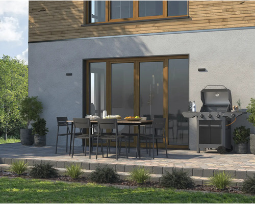 Terasa se zahradním stolem, židlemi a grilem před domem.