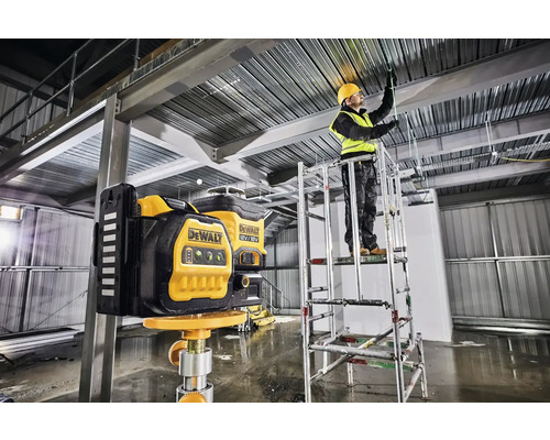 Rotační laser DeWalt používaný na staveništi s pracovníkem na lešení