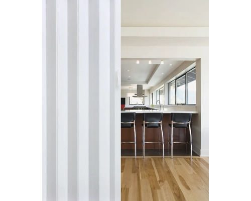 Pohled skrz skládací dveře do kuchyně s pultem a barovými židlemi