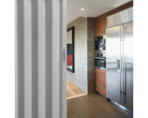 Skládací dveře v kuchyňském prostoru s nerezovými spotřebiči a cihlovou zdí