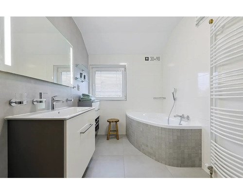 Světlá koupelna s umyvadlem, zrcadlem, vanou a ohřívačem ručníků