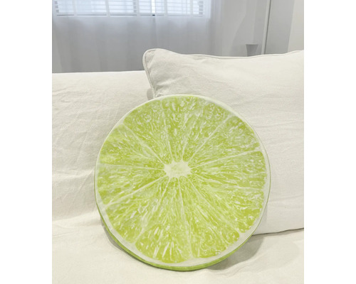 Kulatý polštář s motivem limetky na posteli