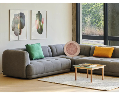 Obývací pokoj s šedou rohovou pohovkou, dekorativní polštáře, konferenční stolek a umění na zdi