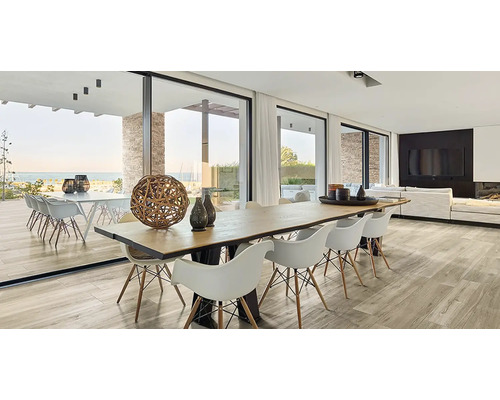 Světlý obývací pokoj s jídelním stolem, židlemi, velkými okny a výhledem na moře