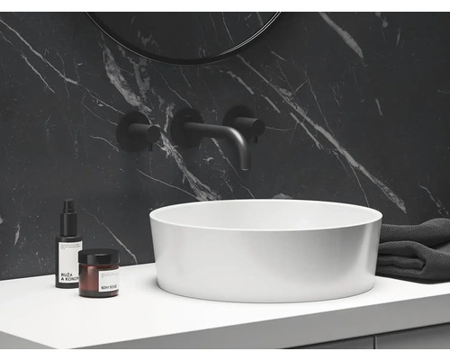 Pohled na koupelnu s umyvadlem na desku, armaturou, ručníkem a kosmetickými produkty na pracovní desce