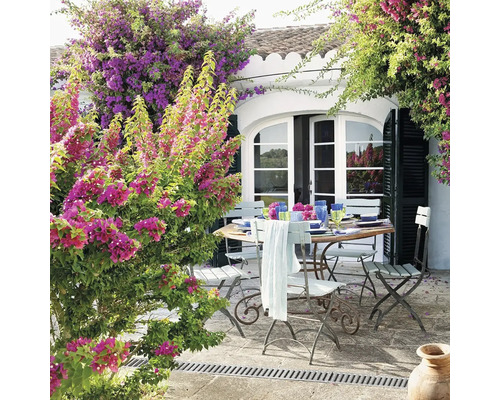 Prostřený zahradní stůl se židlemi na terase s květinami