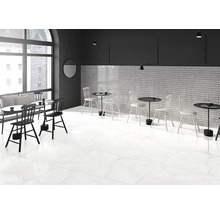 Interiér s bílou dlažbou, stoly a židlemi.