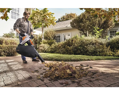 Muž používá vysavač listí Stihl na zahradě k odstraňování listí.