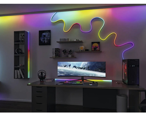 Moderní herní místnost se stolem, počítačovým monitorem, policemi a LED osvětlením pro jasnou a organizovanou atmosféru