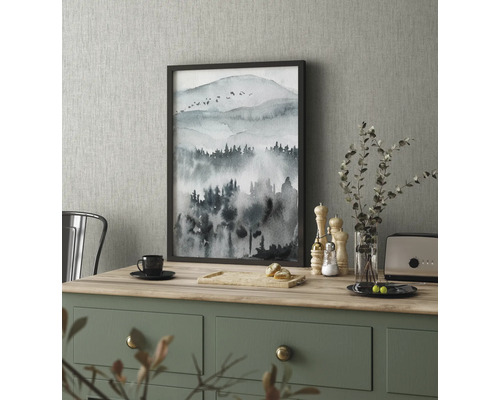 Dekorativní obraz s motivem hory v rámu na kuchyňském stole.