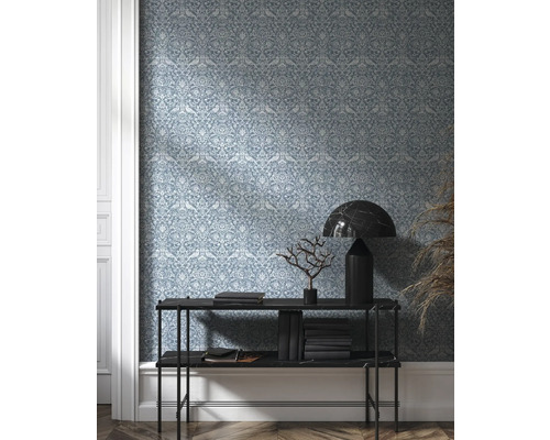 Pohled do místnosti s tapetou se vzorem, konzolou, knihami a dekorací