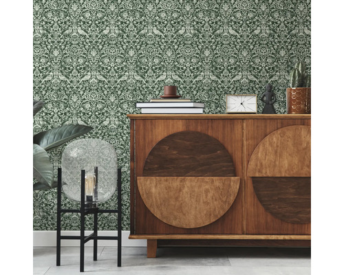 Interiér se zelenou vzorovanou tapetou a dřevěnou skříňkou