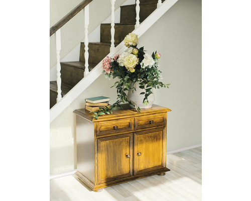 Scéna s dřevěnou komodou, knihami a květinami pod schody