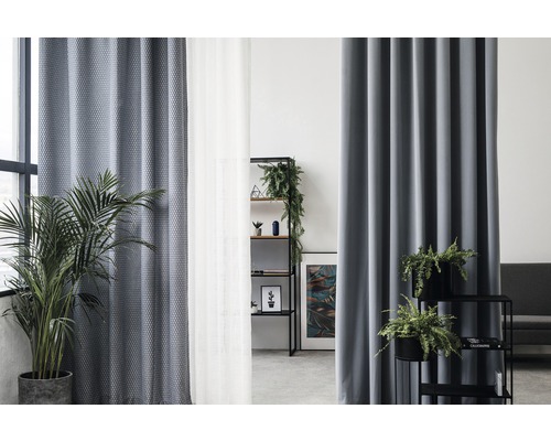 Obývací pokoj se závěsy, regálem a pokojovými rostlinami.