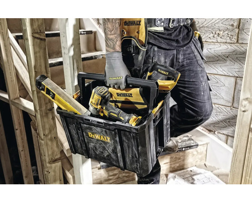 Řemeslník s bednou na nářadí, vodováhou, šroubovákem a pásem na nářadí DeWalt na dřevěném schodišti.