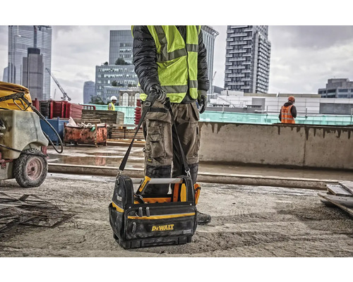 Stavební dělník s brašnou na nářadí značky Dewalt na staveništi.