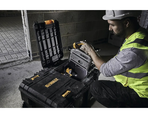 Stavební dělník vyjímá drážkovací frézu do zdiva z kufru na nářadí DeWalt.