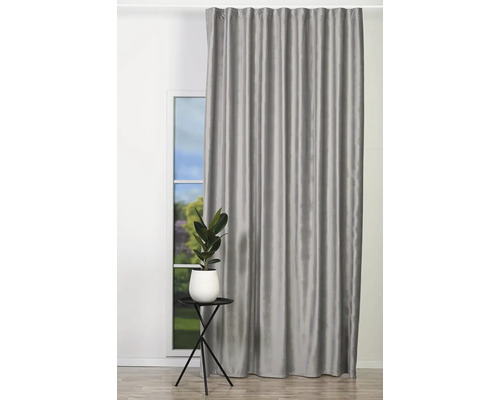 Šedý zatemňovací závěs před oknem s rostlinou na odkládacím stolku