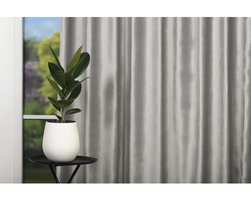 Dekorativní okno se závěsem a pokojovou rostlinou v květináči na malém stolku