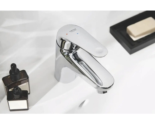 Lesklá vodovodní baterie Grohe na umyvadle s kosmetickými produkty