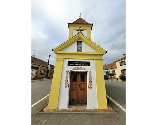 Malá kaple s dřevěnými dveřmi a křížem na střeše