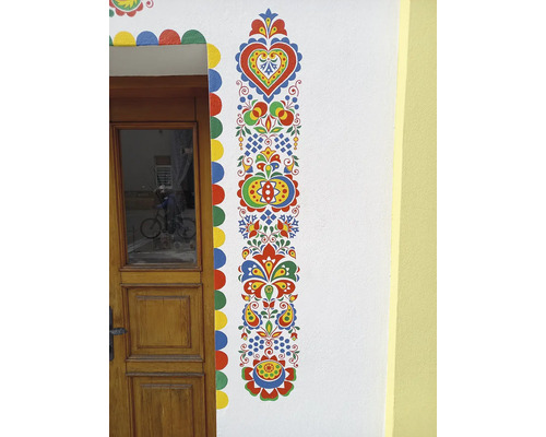 Malovaná fasáda domu s květinovými motivy a dřevěnými dveřmi