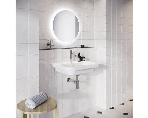 Koupelna s umyvadlem, kulatým zrcadlem s osvětlením a stěnou z bílých dlaždic