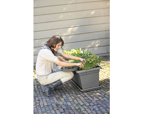 Žena pracuje na zahradě s truhlíkem