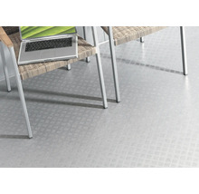 Světlá podlahová krytina s protiskluzovým vzorem pod židlí a notebookem.