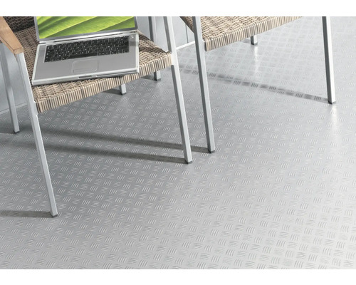 Světlá podlahová krytina s protiskluzovým vzorem pod židlí a notebookem.