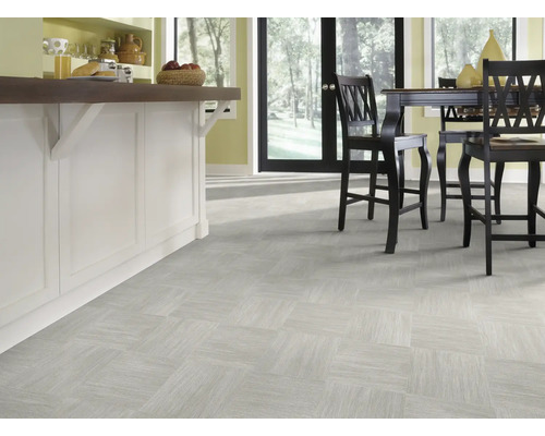 Světlá místnost s dlažbou v čtvercovém uspořádání a kuchyňským ostrůvkem s barovými židlemi