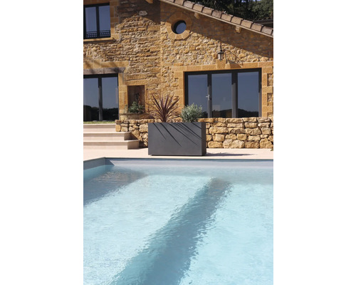 Kamenný dům s bazénem a osázeným truhlíkem na zahradě.