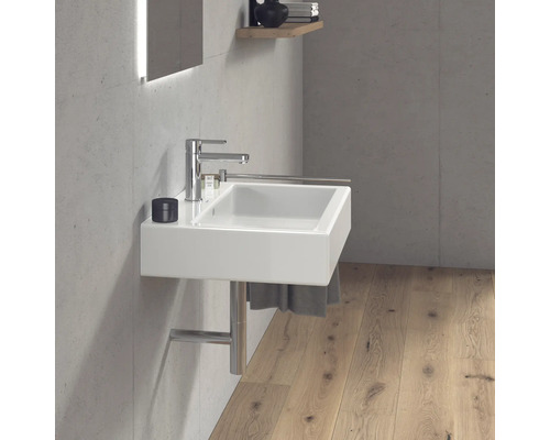 Moderní koupelna s bílým umyvadlem, baterií a držákem na ručníky