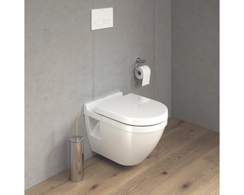 Závěsná toaleta s toaletní štětkou a držákem toaletního papíru na šedé stěně