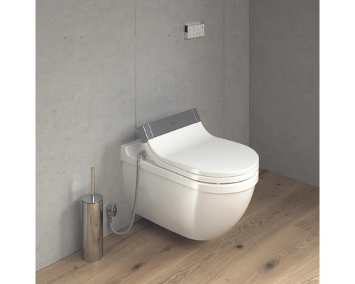 Scéna s toaletou se sprchou, ovládacím panelem a WC kartáčem v koupelně