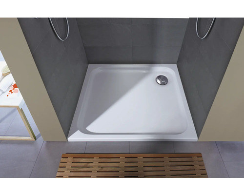 Čtvercová sprchová vanička z litého minerálu v šedém sprchovém koutě s dřevěným roštem.