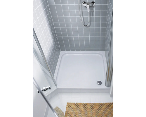 Sprchový kout v úrovni podlahy se sprchovou vaničkou, sprchovou armaturou a sprchovou zástěnou s šedými obklady