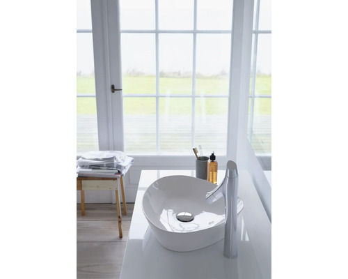 Moderní koupelna s umyvadlem na desku a baterií před oknem.