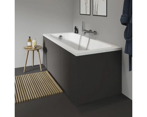 Koupelna s vanou, baterií, dřevěnou koupelnovou rohoží a stoličkou