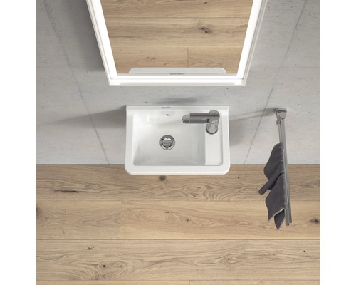 Pohled shora na koupelnu s umyvadlem, zrcadlem a držákem na ručníky.